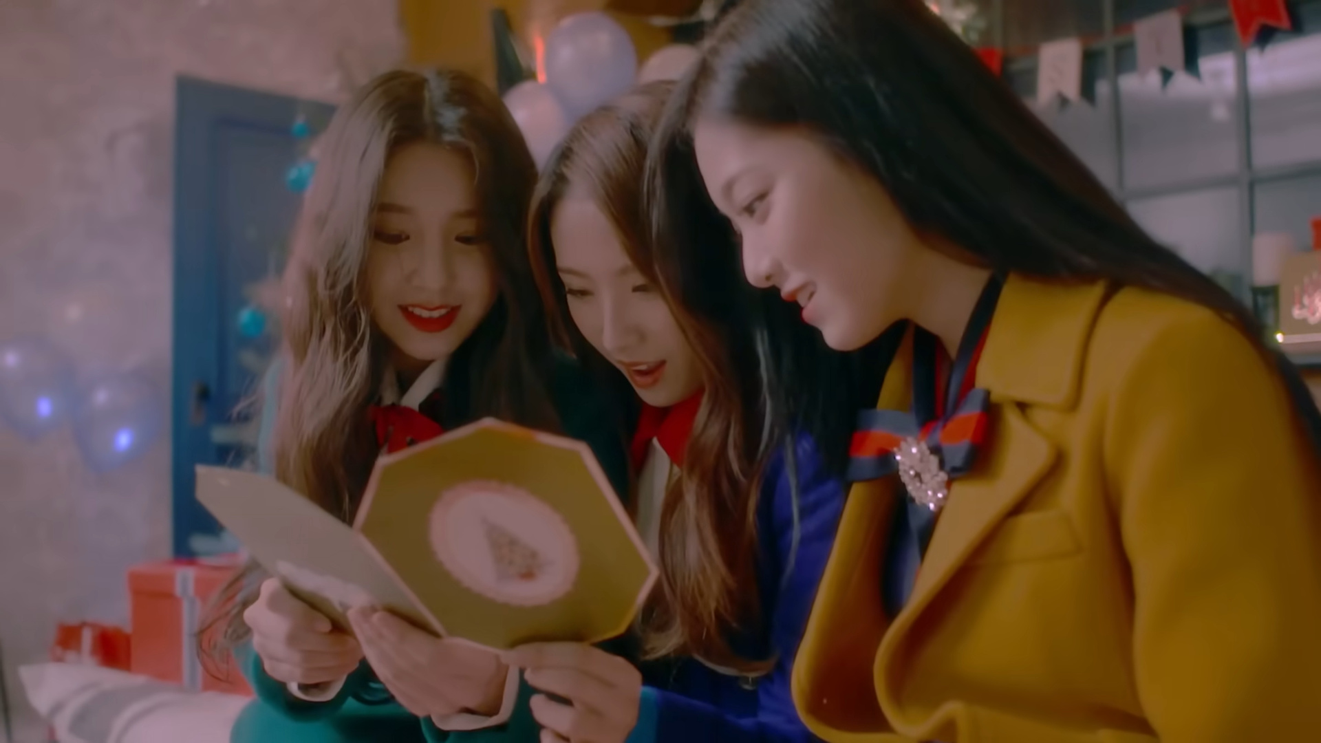 Heejin, Haseul, and Hyunjin reading a Christmas card.